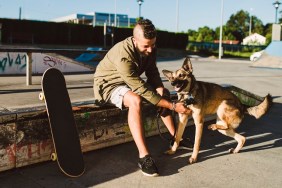 Young man playing with his dog in a skatepark