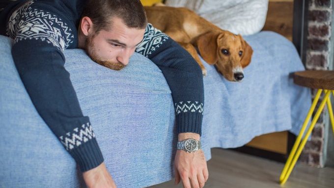 man lying with dog on bed, receiving comfort from canine