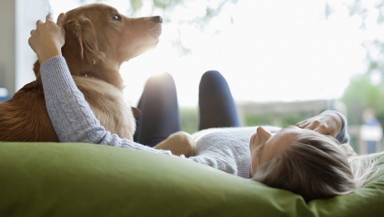 Woman petting dog on bed