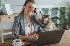 Women at home during pandemic isolation have conference call, pet dog is with her