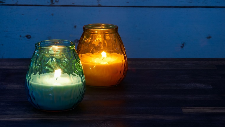 Blue and yellow citronella candles lit in the garden are being used to keep mosquitoes at bay in the late evening