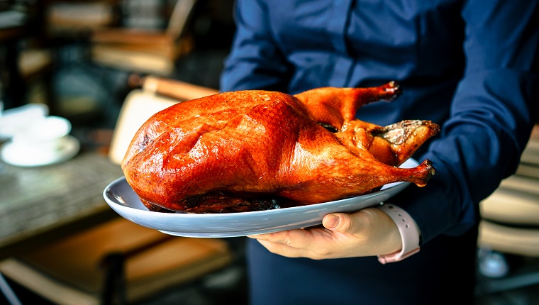 A woman servant holding the Roasted Peking Duck plate for serving