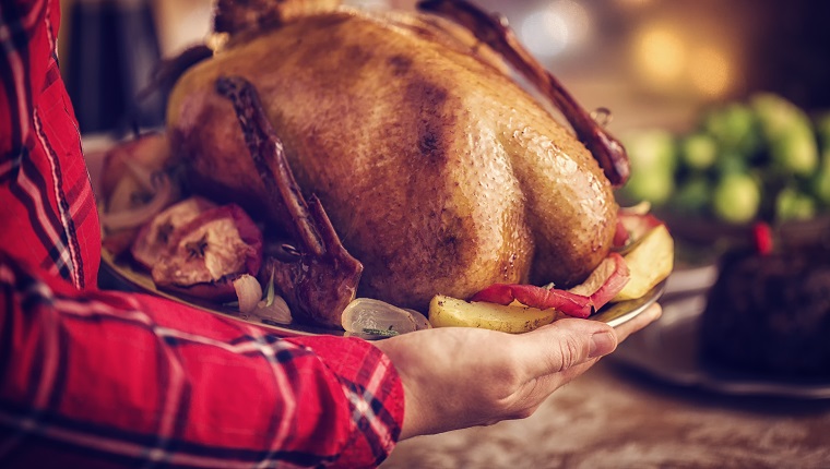 Traditional British holiday goose dinner with apples, brussels sprouts and Christmas Pudding