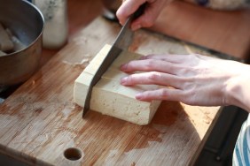 cutting Tofu on the chopping board in Kitchen