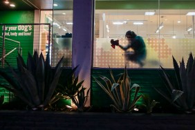 West Hollywood, CA, Wednesday, November 25, 2020 - A worker cleans windows at the Healthy Spot pet spa hours before Covid restrictions require restaurants close at 10 pm, leaving the usually bustling Santa Monica Blvd., less populated.