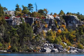 Photo with autumn colors on the trees with a beautiful lake, mountains, and sky in a New York state park - view of cliffs from across the lake