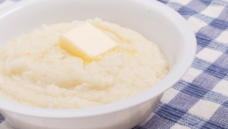 A bowl of white corn grits on a blue plaid placemat