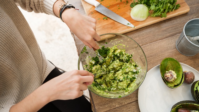 High angle of young woman making guacamole.