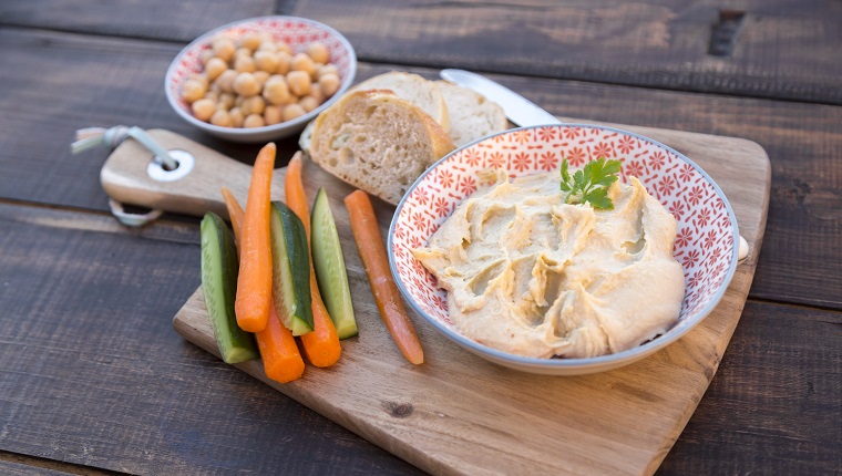 Hummus (Kichererbsencreme), Kichererbsen, Babykarotten, Gurkenstreifen, Baguette, Holztisch, Studio