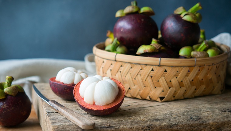 Fresh mangosteen Thai fruits cut in half on wooden table.