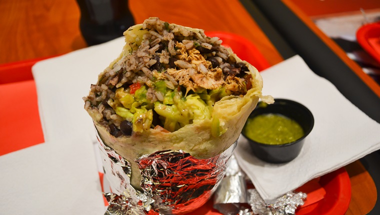 Burrito with meat, rice, bean and vegetables in aluminum foil