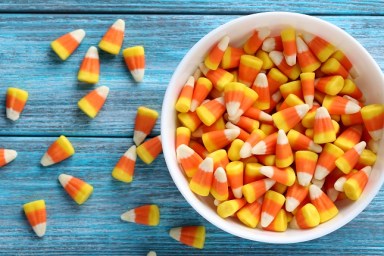 Halloween candy corns in bowl on blue wooden background