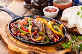 Beef Fajitas with colorful bell peppers in pan and tortilla bread and sauces