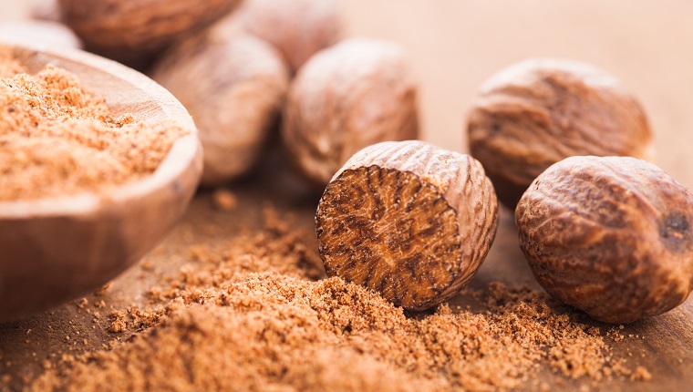 Ground nutmeg spice in the wooden spoon closeup