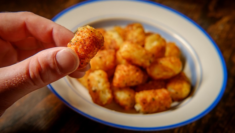 Bowl of fresh crispy potato tater tots on rustic table