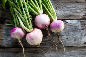 rustic organic turnips with fresh green tops and roots on genuine wood background for sustainable agriculture and vegetarian food, flat lay