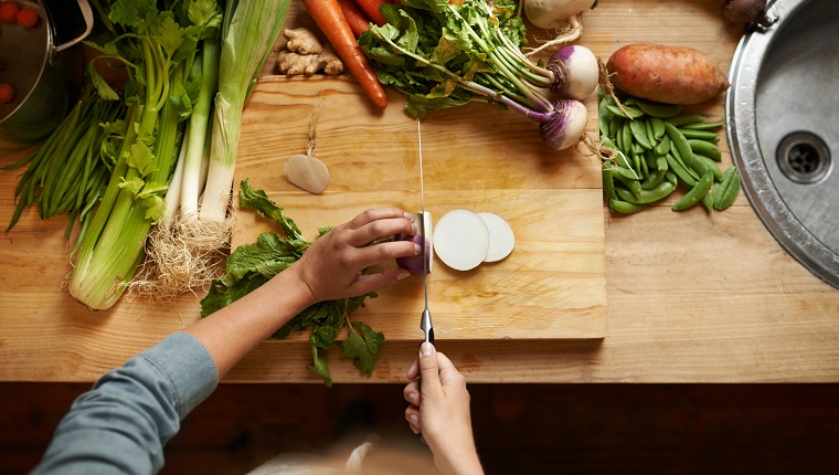 High angle shot of a woman cutting up vegetables on a cutting board