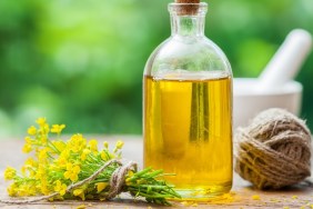 Bottle of rapeseed oil (canola) and repe flowers on table outdoors