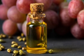 Grape seed oil in a glass jar and fresh grapes