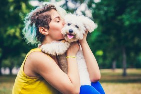 young dog owners kissing their dog in a park