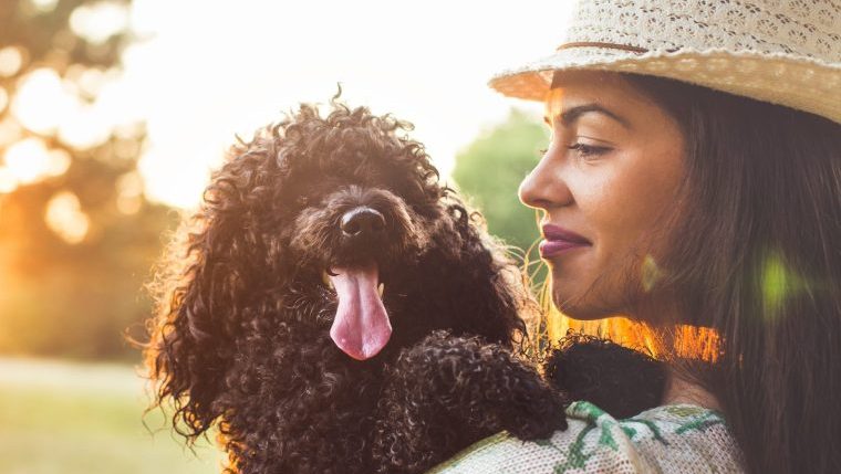 woman hugging poodle best dog breeds for a pisces