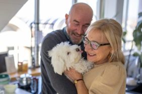 retired couple kissing dog dog spoiled by grandparents