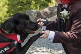 A red-haired woman holding her service dog by the paws, a lady with a hearing disability said her NEADS hearing service dog has changed her life.