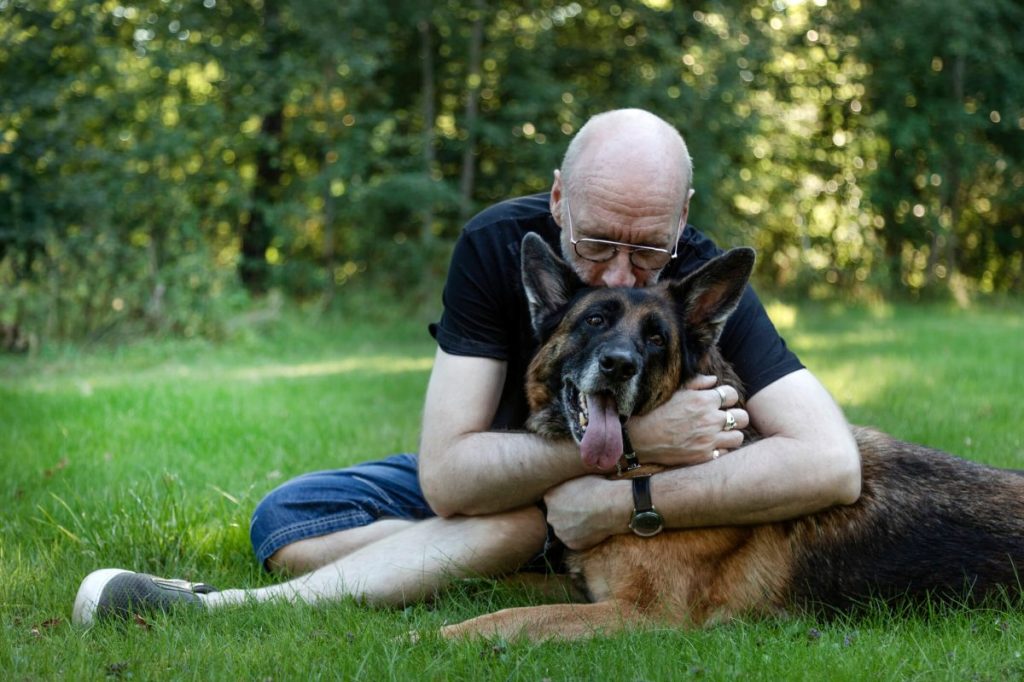 Man hugging German Shepherd dog suffering from osteosarcoma.