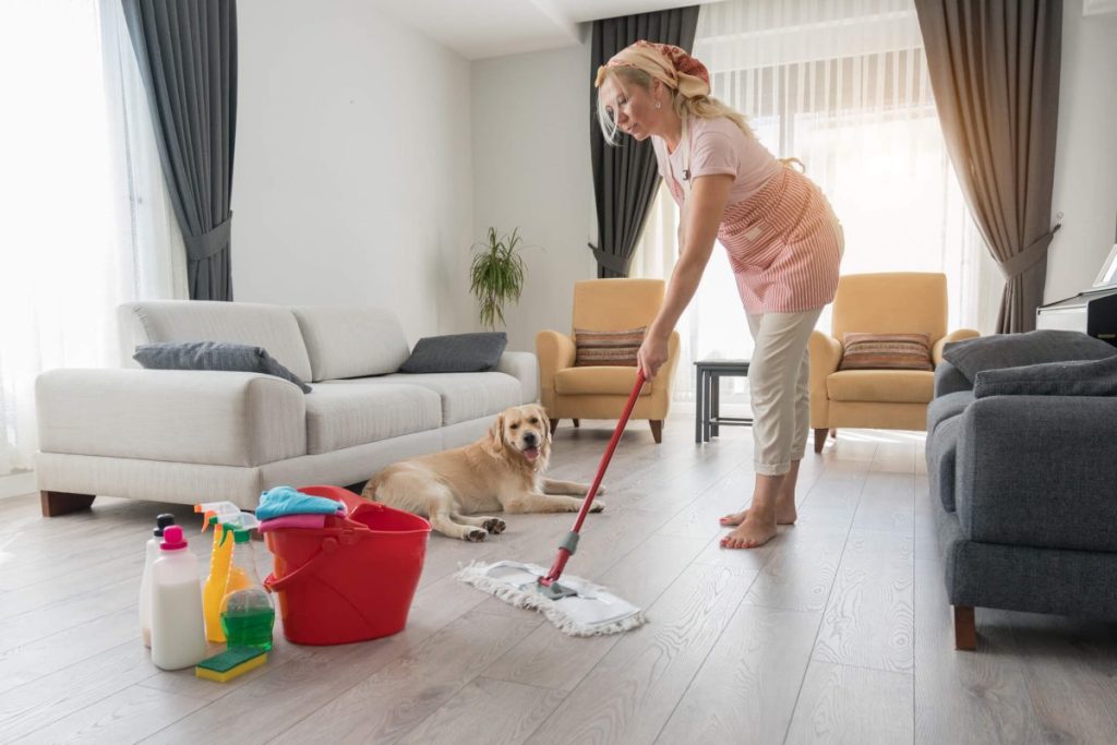 Woman mopping the floor with pet safe cleaning products and disinfectants that won't harm her dog.