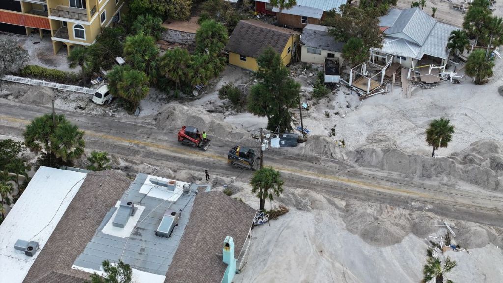 In this aerial view, workers clear the roads of sand and debris after Hurricane Helene hit the area with high surge waters as it passed offshore on September 28, 2024, in Treasure Island, Florida.