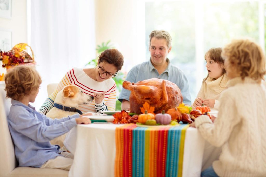 Family and pet at Thanksgiving dinner, with turkey on the dinner table.