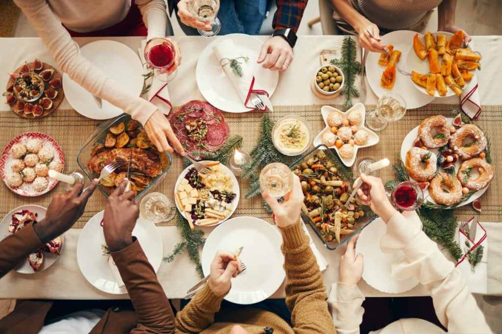 Top view background of people dining at festive Christmas table with delicious holiday food.