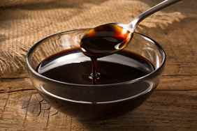 A bowl of molasses with a spoon dripping into it.