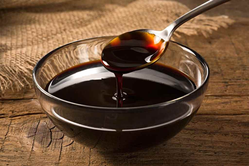A bowl of molasses with a spoon dripping into it.